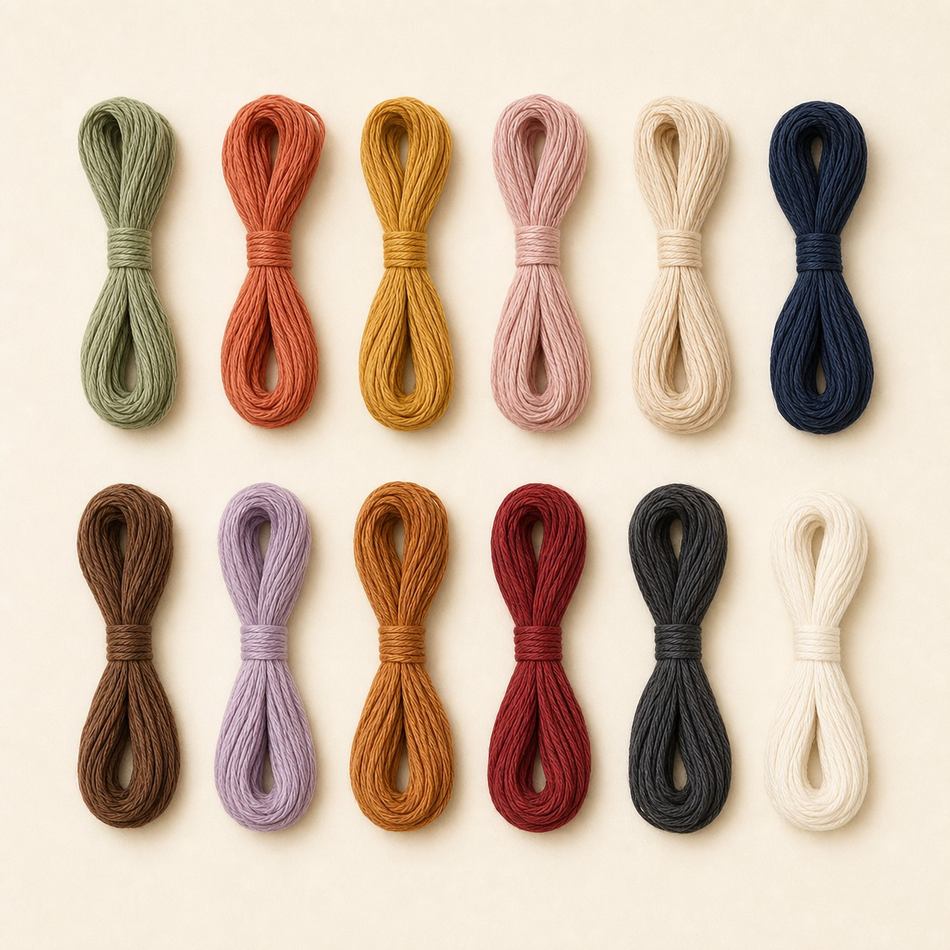Écheveaux de coton mouliné en gradient de couleurs douces sur fond crème